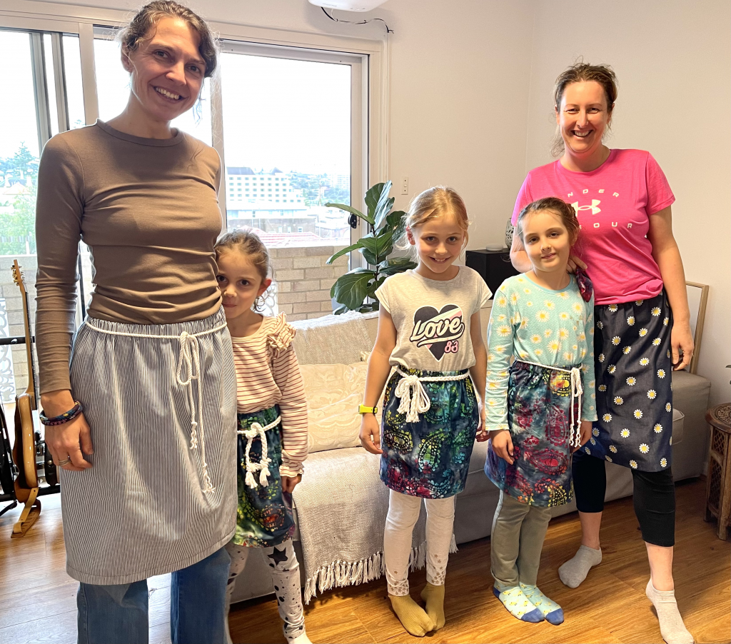 5 people standing and smiling in the sewed skirts