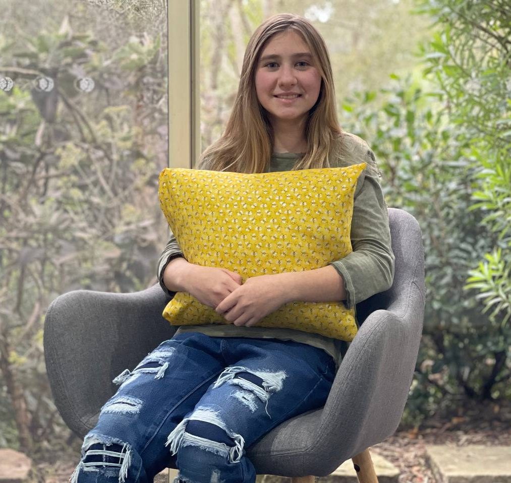 Course participant with bright yellow cushion on grey chair.